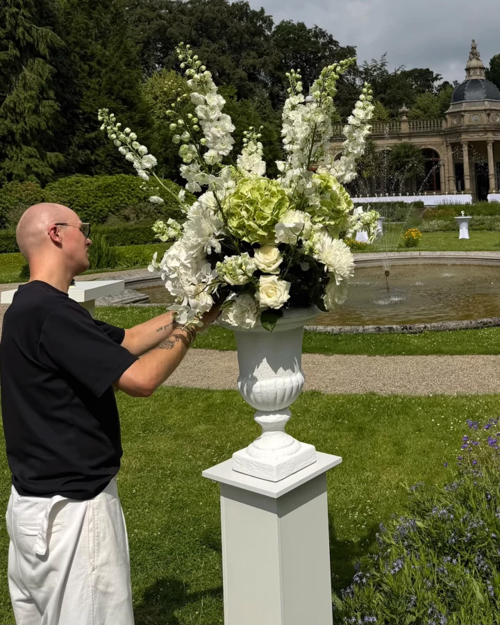 Hosman florist werkt aan groot bloemarrangement op trouwlocatie